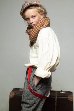 Mükemmel tarzına güveniyor. retro takım elbiseli genç kız. bere çocuk. Kirli suratlı sokak çocuğu. vintage İngilizce tarzı. Eski bavulla seyahat edin. Homelss, ne kadar çok şey var? retro model. Vintage askı