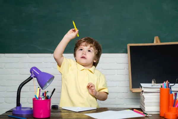 Barátságos gyermek tanteremben közelében tábla íróasztal. Aranyos kis óvodai gyerek fiú vizsgálat egy osztályteremben. Vicces kis gyerekek rámutatva a táblára. — Stock Fotó