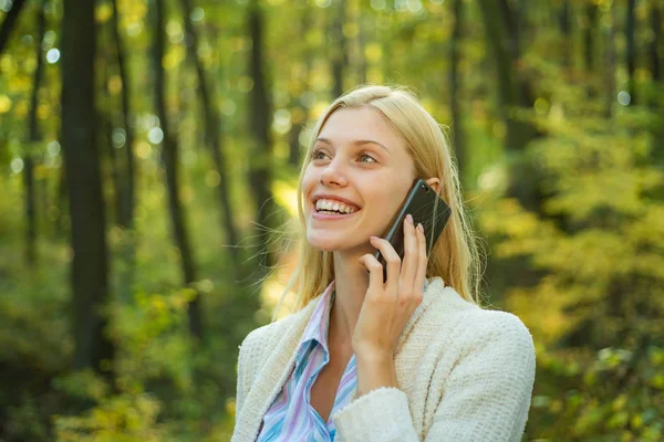 Phone happy outdoor. Blonde woman rejoicing and holding mobile phone in hands. Happy woman using smart phone. Work goals. Surprised young woman using smart phone outdoors.