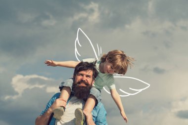 Baba ve oğul. Aile Zamanı. Baba ve çocuk oğlu. Mutlu çocuk oynuyor - uçak. Mutlu baba portresi oğlu omuzlarında piggyback binmek veren ve yukarı bakıyor.