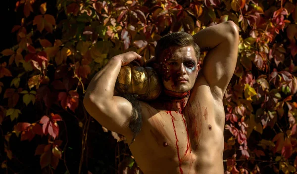 Visage art Halloween. Portrait demi-visage. Portrait d'un horrible zombie effrayant. Jeune homme beau avec le corps musclé posant dans la rue tenant citrouille halloween. Homme zombie musclé effrayant et sanglant . — Photo