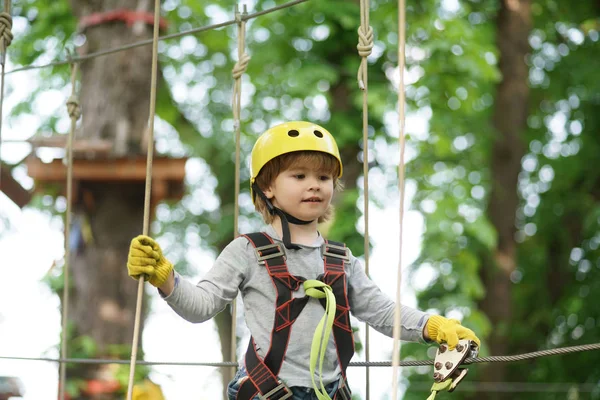 Toddler climbing in a rope playground structure. Cargo net climbing and hanging log. Kids boy adventure and travel. Eco Resort Activities. — Stock Photo, Image