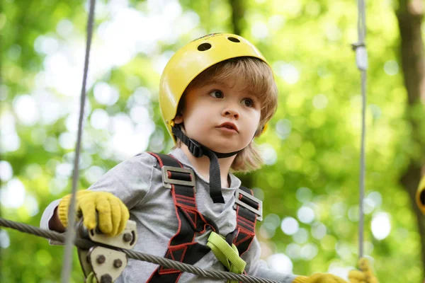 High ropes walk. Helmet and safety equipment. Child concept. Happy Little child climbing a tree. Rope park - climbing center. Active children.