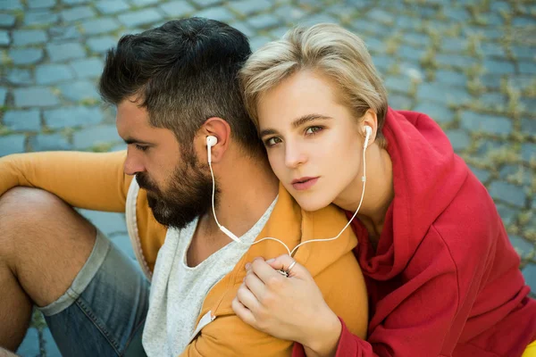 Enjoying music. Feeling free and stylish. Man and woman modern clothes for youth relaxing outdoors. Couple hang out together. Youth just want have fun. Freedom feeling. Forever young. Youth fashion
