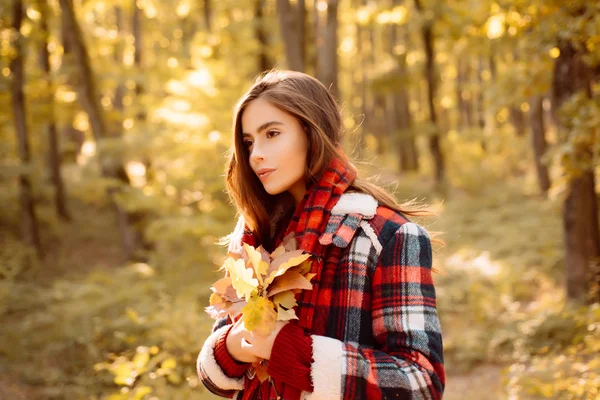 Carefree young woman in trendy vintage red pullover or sweater. Outdoor fashion photo of young beautiful lady surrounded autumn leaves. Autumn landscape. — Stock Photo, Image