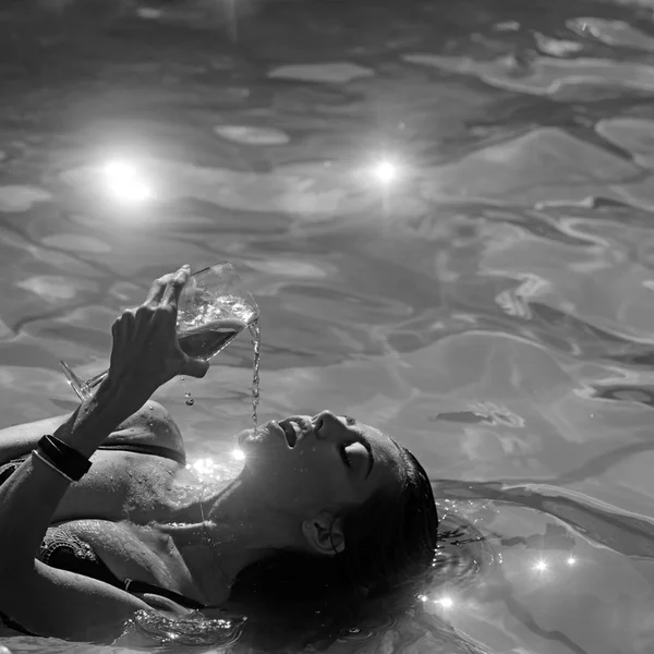 Hermosa mujer acostada en el agua con un cóctel en sus manos . — Foto de Stock