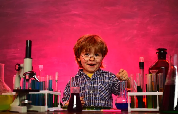 Um miúdo da escola primária. Microscópio de laboratório e tubos de ensaio. Primeira classe. De volta à escola e tempo feliz Kid está aprendendo na aula no fundo do quadro-negro — Fotografia de Stock