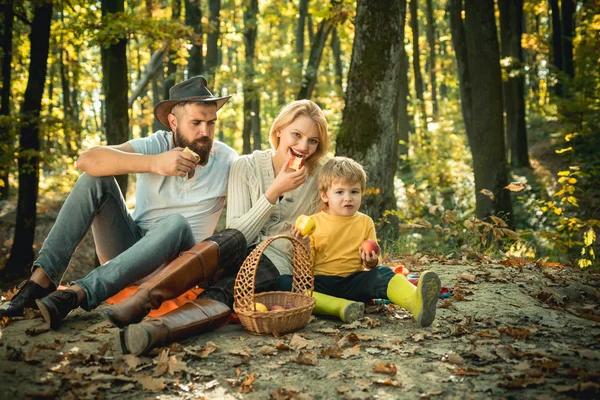 Snack tid. Mor far och liten son picknick. Picknick i naturen. Semester-och turist koncept. Lycklig familj med Kid Boy avkopplande medan du vandrar i skogen. Korg picknick hälsosam mat snacks frukter — Stockfoto