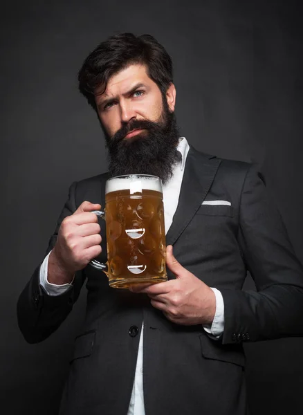 Happy elegant man drinking beer. Senior man in black suit drinking beer with surprise face.