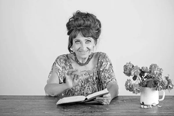 Anciana leyendo libro con gafas en las flores . — Foto de Stock