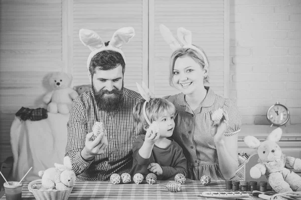 Família que decora ovos de Páscoa na mesa — Fotografia de Stock