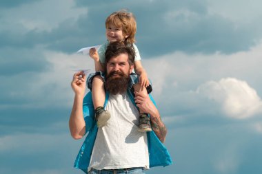 Baba ve oğlu çocuk çocuk dışarıda oynuyor. Mutlu baba, oğluna yazın gökyüzüne geri dönüyor. Ebeveyn -lik. Mutlu baba yaz aylarında gökyüzüne oğlu geri binmek veren.