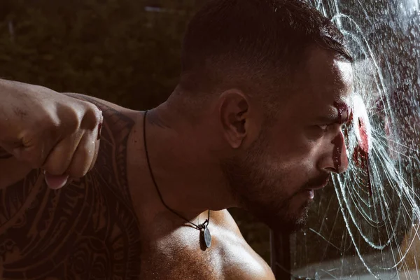 Attack in force. Strong latino man trying to hit or attack glass wall. Muscular hispanic man performing powerful attack with his fist. Attack the probem — Stock Photo, Image