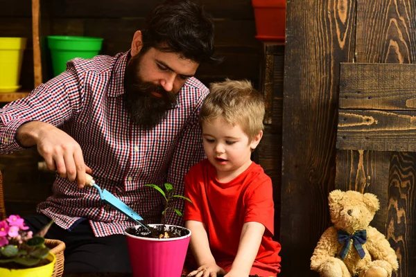 Flower care watering. Soil fertilizers. Father and son. Fathers day. Family day. Greenhouse. happy gardeners with spring flowers. bearded man and little boy child love nature. Welcome to our world