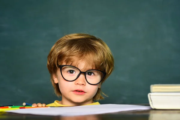 Joli petit garçon d'âge préscolaire dans une classe. Arrière-plan tableau noir. Journée des professeurs. Des enfants de l'école primaire. 1er septembre - Salle de classe. — Photo