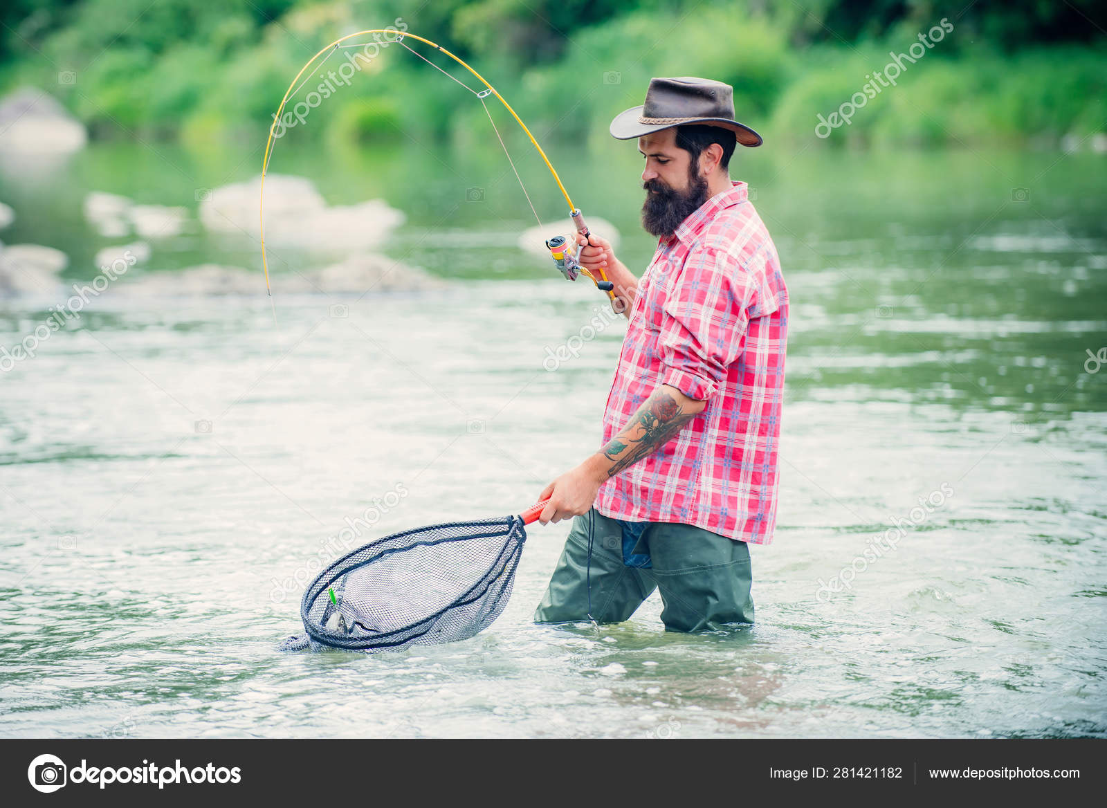 Holding brown trout. Man with fishing rods on river berth. Men fishing in  river during summer day. Fly fisherman using fly fishing rod in beautiful  river. Stock Photo by ©Tverdohlib.com 281421182