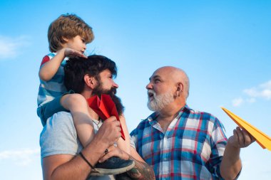 Aile bireyleri. Uçak uçmaya hazır. Erkek çok nesilli bir aile. Gökyüzü arka plan karşı oyuncak jetpack ile çocuk pilot. Mutlu babalar günü.
