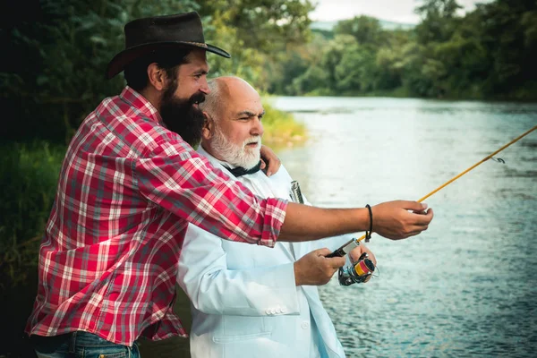 飞棒和卷轴与棕色鳟鱼从溪流。父亲和儿子一起放松。男人在夏天在河里钓鱼。男子钓鱼. — 图库照片