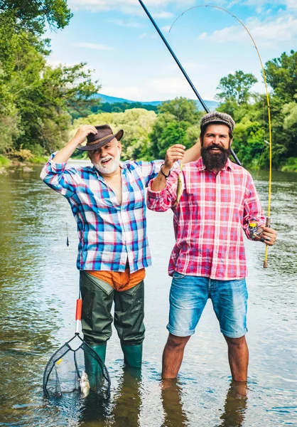 Menschenfischen. Männer angeln im Fluss während des Sommertages. Vater und Sohn angeln. Fliegenrute und Walze mit einer Bachforelle aus einem Bach. — Stockfoto