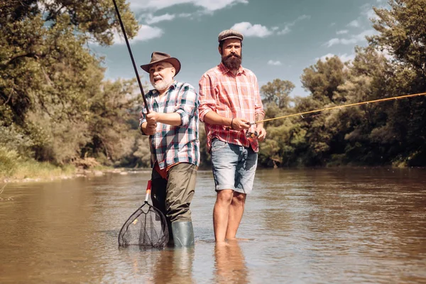 Mutlu baba ve oğul birlikte nehir üzerinde güzel gökyüzü altında yaz günü balıkçılık. Balıkçı ve kupa alabalığı. Hala su alabalık balıkçılık. — Stok fotoğraf