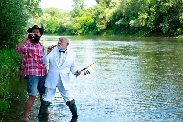 Padre e hijo relajándose juntos. Pescador. Hombre pescando. Feliz abuelo y nieto con cañas de pescar en la litera del río. Feliz padre e hijo pescando en el río sosteniendo cañas de pescar . — Foto de Stock