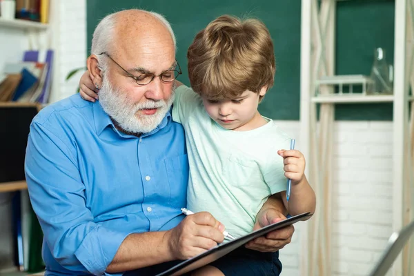 Schattige kleine Preschool Kid jongen met grootvader in een klaslokaal. Jongen van de basisschool op de school werf. Een grootvader en een peuter leren in de klas. Weinig klaar om te studeren. — Stockfoto