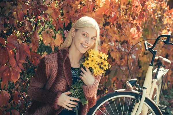 Dívka s bicykly a květinami. Žena s cyklistickou zahradou. Víkendová aktivita. Aktivní volný čas a životní styl. Holka jezdí na kole pro zábavu. Blondýna se těší relaxační zahradě. Podzimní kytice. Teplý podzim — Stock fotografie