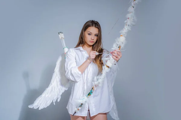 Día de San Valentín Cupido. El Dios del Amor. La postal para el Día de San Valentín - el espacio de copia. Lindo poco hembra Cupido dispara un arco. Chica inocente. Dulce chica con traje de ángel vestido blanco y alas de plumas . — Foto de Stock