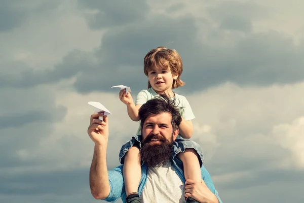 Ojciec i syn. Ojciec dając Syna jeździć na powrót w parku. Ojciec i syn w parku. Wolność snu-radosny chłopiec bawią się papierowym samolotem. — Zdjęcie stockowe