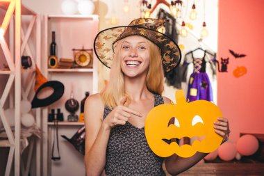 Şapka ve süpürge pembe arka plan üzerinde duran siyah cadı kostümü güzel genç kadın. Geniş Cadılar Bayramı parti sanat tasarımı. Cadılar Bayramı dekoru. Tonlu görüntü. Kopyalama alanı.