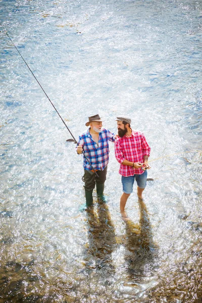 Heureux grand-père et petit-fils avec des cannes à pêche sur le quai de la rivière. Joyeux concept de famille père et fils ensemble. Pêche à la mouche de la truite . — Photo