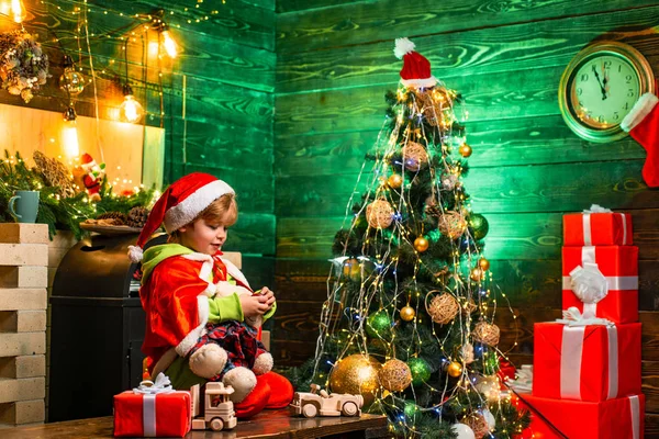 Navidad del día de familia. Regalos y sorpresas. Lindo niño pequeño jugar cerca del árbol de Navidad. Feliz Navidad y feliz año nuevo. Los niños disfrutan de las vacaciones de invierno en casa. Hogar lleno de alegría y amor — Foto de Stock