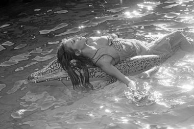 şişme timsah ve kadın havuzda. suda kadınla şişme yatak