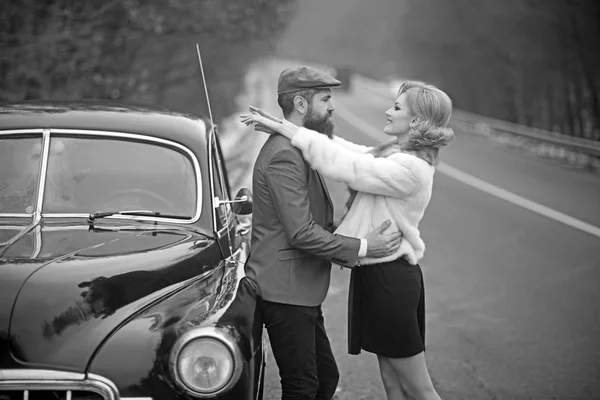 Travel and business trip or hitch hiking. Bearded man and sexy woman in fur coat. Retro collection car and auto repair by mechanic driver. Escort of girl by security. Couple in love on romantic date