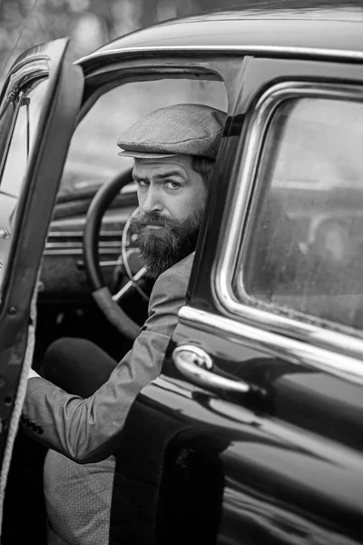 Er genießt seinen Roadtrip. fröhlicher junger Mann blickt in die Kamera und hält die Hand am Lenkrad, während er in seinem Retro-Auto sitzt. — Stockfoto