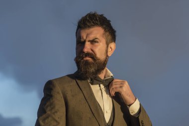 Sakallı ve ciddi yüzlü işadamı. Yönetici mavi gökyüzü arka plan üzerinde takım elbise ve papyon giymek. İş ve başarı kavramı