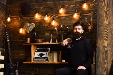 Rahat sıcak bir atmosferde adam içiyor. Adam sakallı ısınma içecek, ahşap arka plan ile akşam keyfini çıkarın. Sakallı adam sıcak mevsimlik içecek bir bardak sıcak şarap tutar. Rahatlatıcı bir akşam