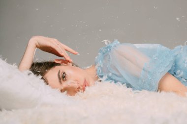 Kız sakin yüzünde tüyler ve kabartmak ile kaplı yatakta yatıyordu. Yumuşak ve nazik bir kavram. Yatak, gri arka plan şeffaf mavi geceliği Bayan yatıyordu. İhale pijama rahatlatıcı uzun saçlı kadın