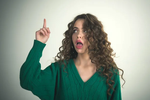 Girl with curly hair at hairdresser at white wall. girl hold raised finger and have an idea. — Stock Photo, Image