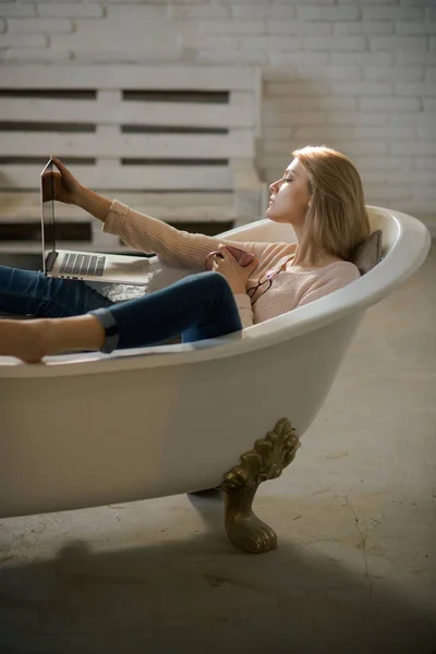 女人在家用浴室里用电脑工作。感性的女人在洗澡与电脑. — 图库照片