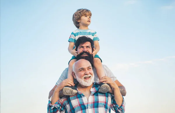 男性世代:祖父の父と孫がカメラを見て抱き合い、微笑んでいる。父の日の概念。ジェネレーションコンセプト。週末の家族の遊び。異なる年齢の男性. — ストック写真