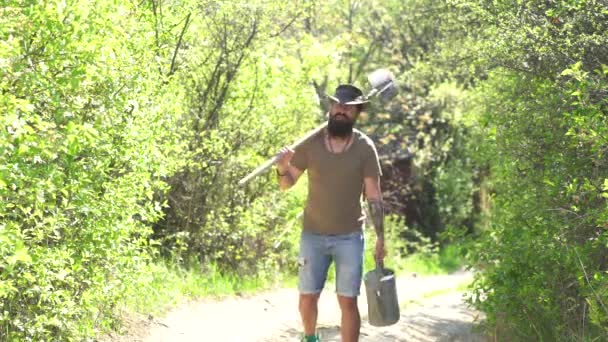 Farmer öntözés a hajtás a területen. Szakállas farmer, lapáttal. Ember tartsa lapát. Nyugati cowboy viselt cowboy kalap-közelről portré. A föld napja. Öko-élet. — Stock videók