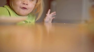 Gülme sevimli çocuk erkek bebek mama sandalyede oturan ve mutfak arka planda yemek. Ebeveyn -lik. Evde kahvaltı olan güzel çocuğun portresi. Sevimli çocuk evde kahvaltı yeme.