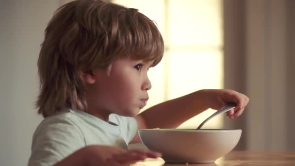 Un bambino felice fa colazione. Cibo e bevande per bambini. Bambino carino che fa colazione a casa. Un ragazzino che fa colazione in cucina. Gustosa colazione per bambini . — Video Stock