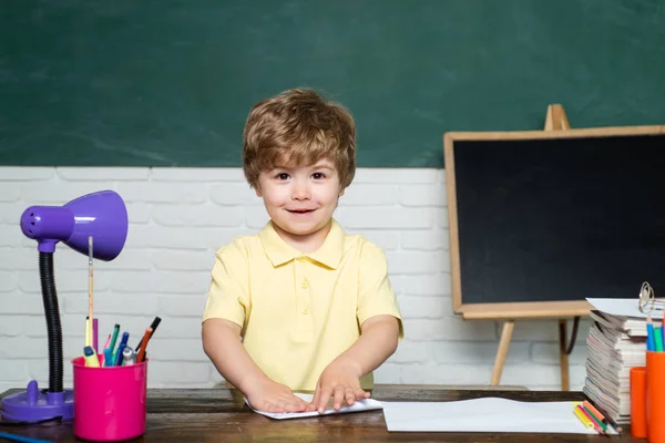 Wesoły uśmiechnięty dziecko na tablicy. Wesoły uśmiechnięty mały chłopak uczeń zabawy przeciwko koncepcji szkoły tablica. Dzieci z książką. — Zdjęcie stockowe