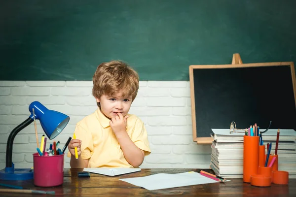 La prima volta a scuola. Giorno di insegnanti - concetto scolastico. Un ragazzino buffo che punta sulla lavagna. Scuola per bambini . — Foto Stock