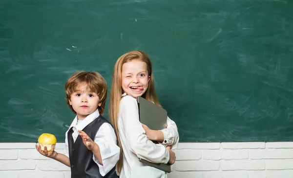 Ιδέα της Apple και της Σχολής βιβλίων. Κορίτσι και αγόρι με ευτυχισμένο πρόσωπο κοντά στο γραφείο με σχολικές προμήθειες. Αντιγραφή χώρου. Μαθήματα σχολείου. Δημοτικό σχολείο και εκπαίδευση. — Φωτογραφία Αρχείου