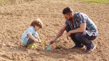 Eko çiftlik işçisi - baba ve oğul kavramı. Sevimli baba ve oğlu bahar alanında spud ile çalışıyor. Eco Resort Faaliyetleri. Erken çocukluk gelişimi. Bebek yaşı. Ekoloji kavramı çocuk.