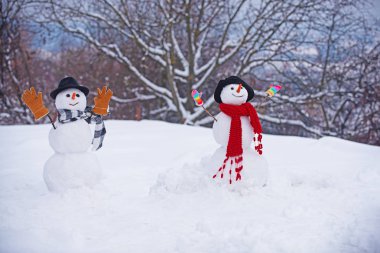 Hediye kutularıyla kışın Noel manzarasında duran mutlu kardan adam. Kar tarlasında şık şapkalı ve eşarplı komik kardan adam. Kardan adamlar.