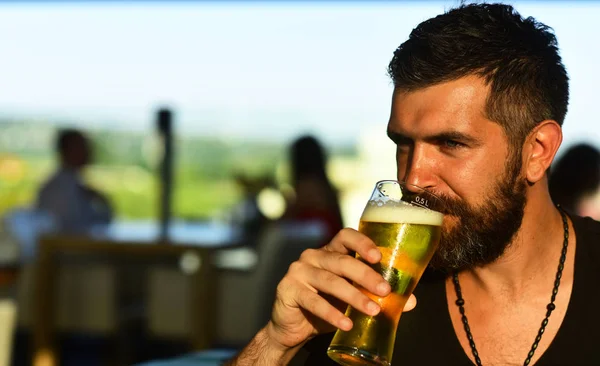 Бородатий чоловік п'є пиво. Старший чоловік пив пиво з несподіваним обличчям. Чоловік тримає келих пива . — стокове фото